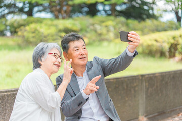 屋外でスマホを使って写真や動画を撮る高齢者夫婦
