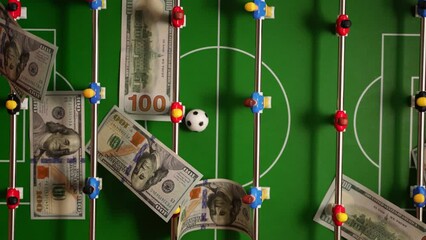 Table football game and falling dollar bills. - Powered by Adobe
