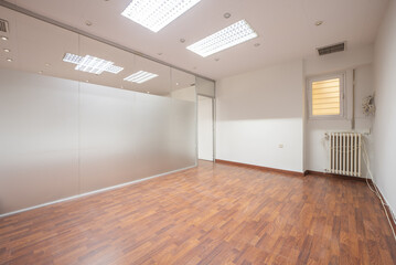 Fototapeta premium An empty office with a wall of glass partitions, jatoba-colored laminated floors and technical ceilings