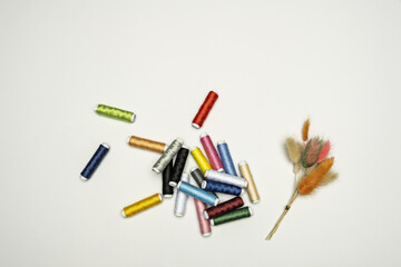 Many new spools of thread in all colors along with a small bouquet of decorative dried plants