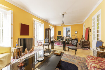 Living room decorated with profuse eclectic furniture, Persian rugs, pinewood floors and several...