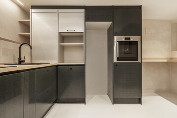 Kitchen with green furniture, black handles, cabinet with aluminum shutters and empty space for the fridge