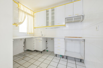 kitchen with used white furniture without appliances, with yellow details and matching curtains