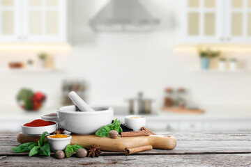 Mortar and different spices on wooden table in kitchen. Space for text