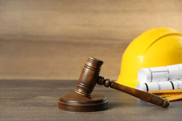 Construction and land law concepts. Judge gavel, protective helmet with drawings on wooden table,...