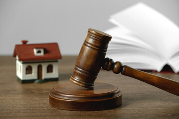 Construction and land law concepts. Judge gavel, open book with house model on wooden table