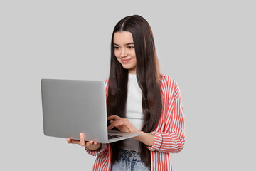 Naklejka premium Teenage girl with laptop on light grey background
