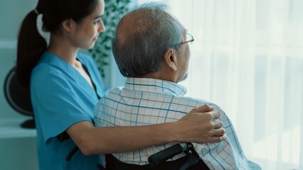 Rear view of a caregiver and her contented senior patient gazing out through the window. Elderly...