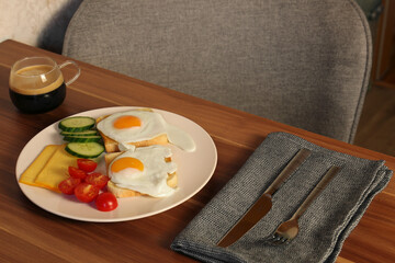 Tasty toasts with fried eggs, cheese and vegetables on wooden table