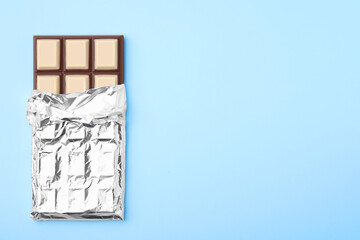 Tasty chocolate bar on light blue background, top view. Space for text