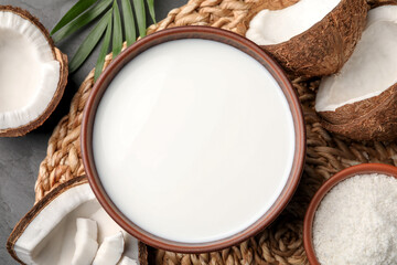 Fototapeta na wymiar Bowl of delicious vegan milk near coconut pieces on grey table, flat lay