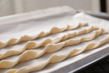 Homemade breadsticks on baking sheet, closeup. Cooking traditional grissini