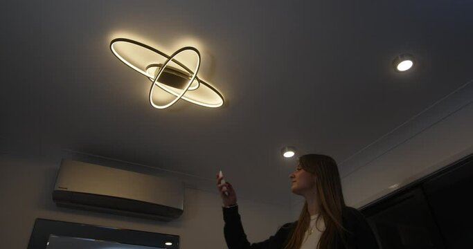 female model walking in changing colour temperature of LED ceiling lights with remote control from warm white to cool white and then walking out