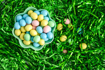Fototapeta na wymiar Bowl of candy coated easter eggs in a nest of easter grass, as a holiday background 