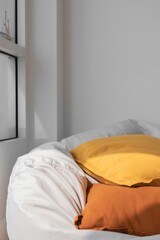 Fototapeta na wymiar White beanbag with yellow and orange pillows in the corner of living room.