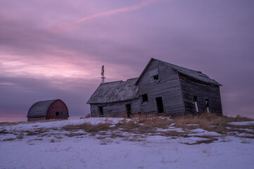Abandoned homestead and out buildings in rural, Alberta during winter.