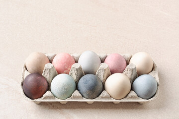 Natural dyed Easter eggs In paper box on beige table as copy space. Eco concept. Pastel pale colors.