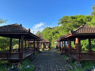 Panoramic view of public park with row of wooden gazebo on the both side and natural background.