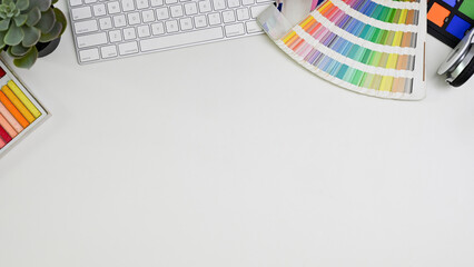 Top view of a minimal white graphic designer's desk with accessories and copy space.