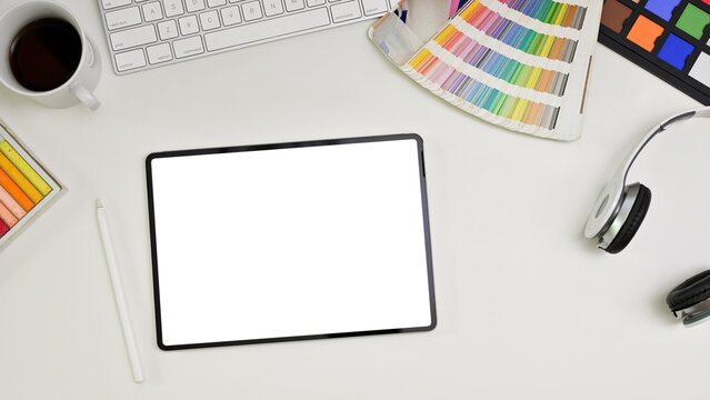 Top view of a modern minimal white graphic designer office desk with tablet mockup.