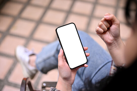 Close-up image of an Asian woman holding a smartphone mockup and showing clenched fist
