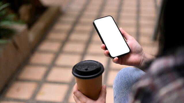 Close-up image of an Asian woman sipping coffee and using her smartphone. phone white screen