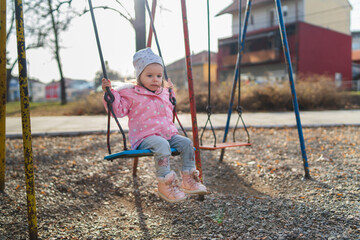 A one young baby girl is swinging on swing in the park during the day