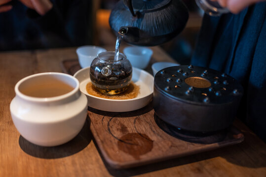 Woman pouring hot water in a teapot close-up view on a wooden table