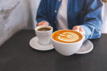 Closeup image of a woman holding and serving two cups of hot coffee
