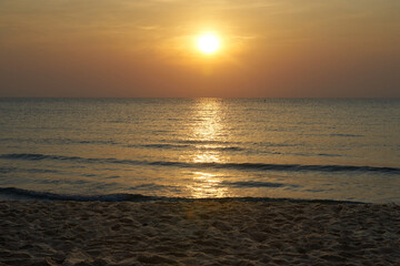 orange sun on sky background with sea wave and beach sand
