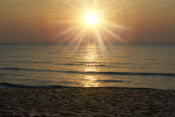 sun with starburst light flare on sky  background and sand sea wave foreground