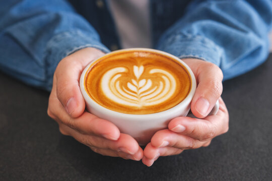 Closeup image of a woman holding coffee cup on the table