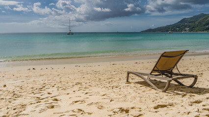 A chaise longue stands on a tropical beach. Footprints in the sand. The waves of the turquoise...