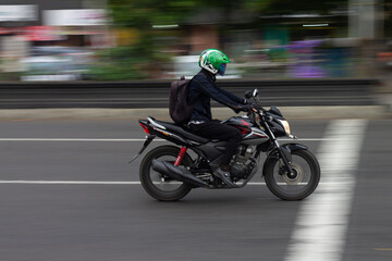 Photo of a young man riding a sports motorbike, taken with the blur technique