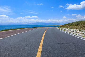 Naklejka premium Asphalt road and lake with sky clouds natural scenery in Xinjiang, China.