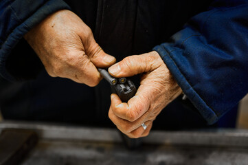 Fototapeta premium Senior worker puts bullets into gun magazine at factory