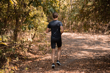 Caucasian handsome sportsman jogging workout wellness concept, athletic running in nature autumn...
