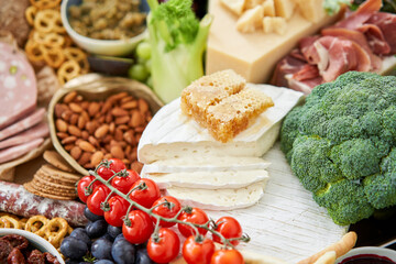 Brie cheese with honey close-up. Table full of mediterranean appetizers, tapas or antipasto. Assorted Italian food set. Delicious snack on party or picnic time. Italian style banquet. 