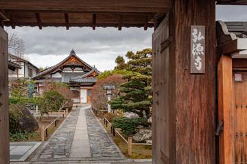 Traditional wooden buddhist temple building architecture exterior and garden framed by a wooden entry door of the Tenryu-ji Buddhist temple in Kyoto Japan