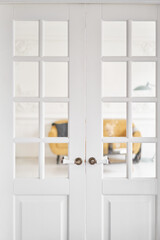 Old-style door, white - handle. The interior of a bright living room in a modern apartment.