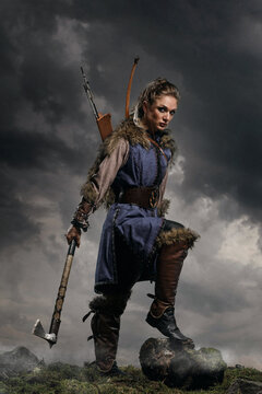Beautiful female viking woman warrior in battle with ax and bow with arrows. Amazon fantasy blonde