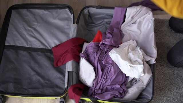 Traveler packing a suitcase for a trip at home throws things and clothes, top view. Woman packing suitcase at home. Travel concept.