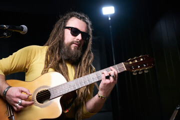 Obraz premium Guitarist man plays an acoustic guitar Close-up at studio