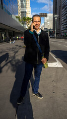 Executive man walks down the avenue with his smartphone towards work