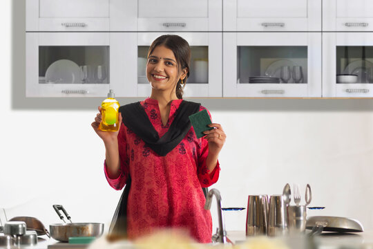 Cheerful woman holding dish wash and scrub pad