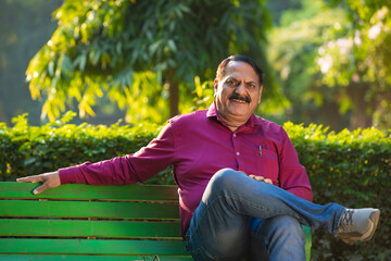 Obraz premium Indian man relaxing on bench in park.