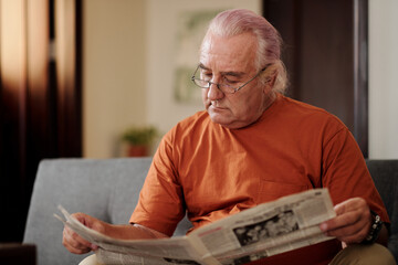 Senior man in glasses reading newspaper
