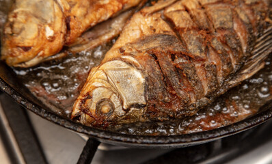 The fish is fried in oil in a frying pan.