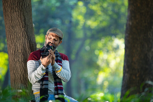 Indian man taking some photo and using camera at garden.