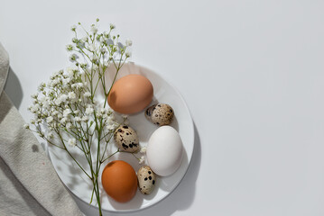 Aesthetic minimalist Easter table setting, eggs and flowers on white plate, on neutral background....